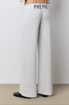 A model shown from the back wearing light heather gray waffle knit wide-leg pants with 'PHE PHE' printed on the elastic waistband, paired with a matching light gray hoodie and black flats.