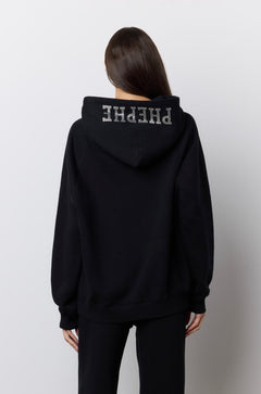 A model viewed from behind wearing a black hoodie and matching wide-leg pants with rhinestone 'PHEPHE' lettering on the hood and legs, standing against a plain light gray wall.