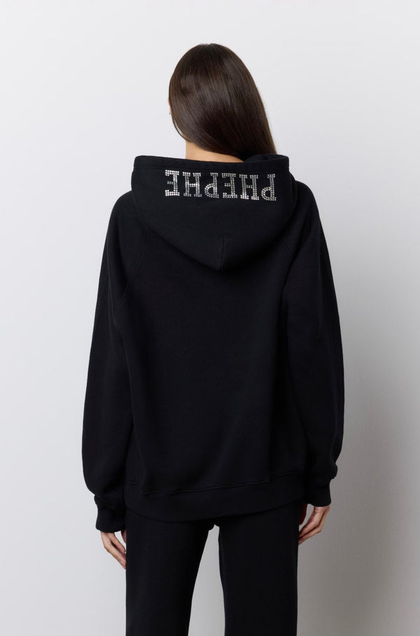A model viewed from behind wearing a black hoodie and matching wide-leg pants with rhinestone 'PHEPHE' lettering on the hood and legs, standing against a plain light gray wall. |M1