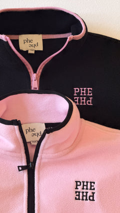 Two fleece quarter zip sweatshirts laying stacked on a table with embroidered "PHE PHE" lettering on left chest.